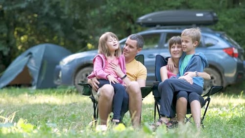 Affectionate Family Sits Together While Camping Outdoors