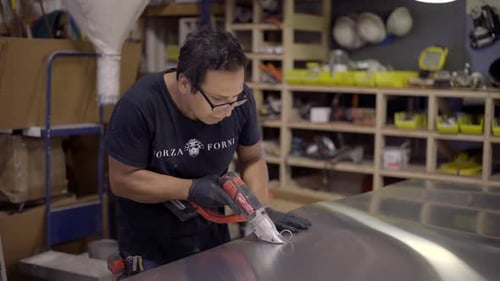 Worker cutting sheet metal in a shop