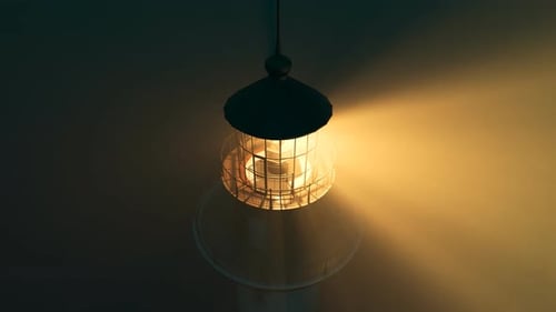 Lighthouse light spinning around. Tall tower standing on the coastline.