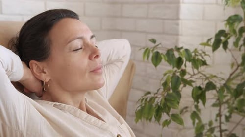 Woman Relaxing in Armchair with Eyes Closed