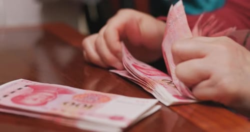 Hands Counting Chinese Renminbi Currency on Table