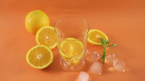 Adding Orange Slices to Refreshing Glass Drink