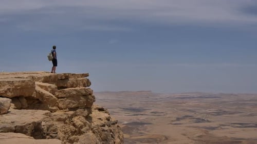 Mann mit Rucksack steht auf der Felswand des Desert Mountain Rock