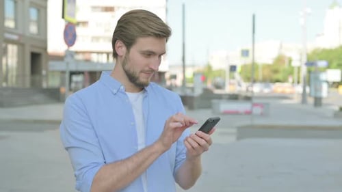 Young Adult Male Celebrating Mobile Phone Success