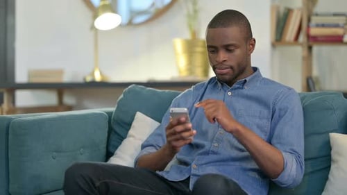 Young Adult Using Smartphone on Couch at Home