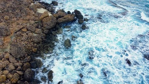 Sea Waves Washes the Rocky Shore Above Aerial Shot Flying Over Coastline Cliffside with Blue Pure