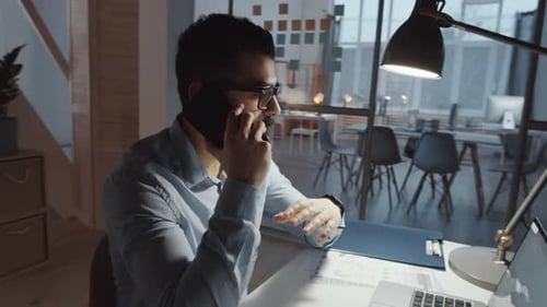 Middle Eastern Male Manager Having Phone Talk at Office Desk