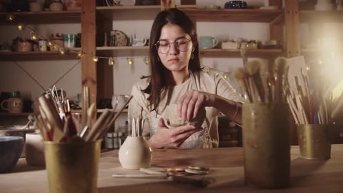 Young Woman Potter Forming a Bowl Out of Soft Clay with Her Hands in the Art Studio