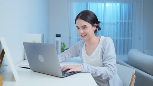 Young Woman Typing on Laptop at Desk Indoors