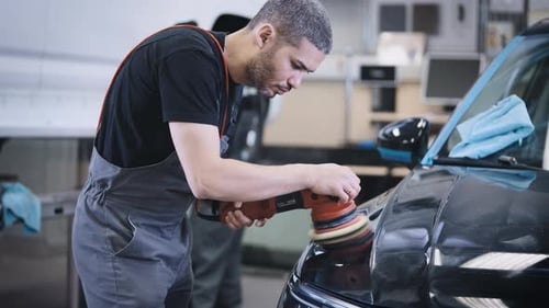 Mechanic Polishing Car with Powered Buffer in Auto Garage