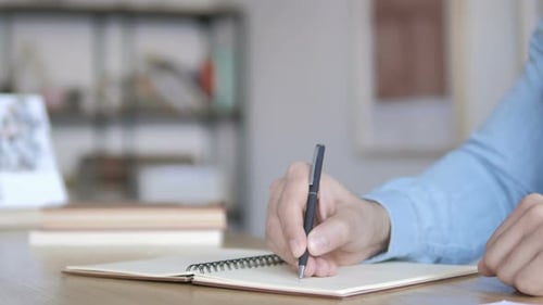 Close Up of Hand Writing In Notebook