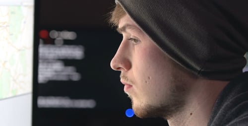 Young Adult Looks at Computer Screen Wearing Beanie