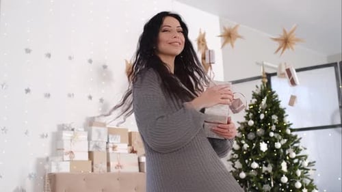 Woman Holding Present By Christmas Tree