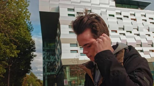 Young Adult Puts in Wireless Earbuds Outdoors
