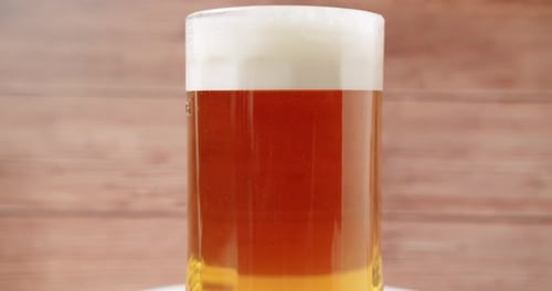 Basteln Sie volles Bier in den großen Glasbierkrug auf Holzuntergrund
