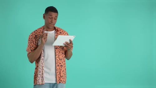 Young Adult Using Tablet in Front of Blue Background