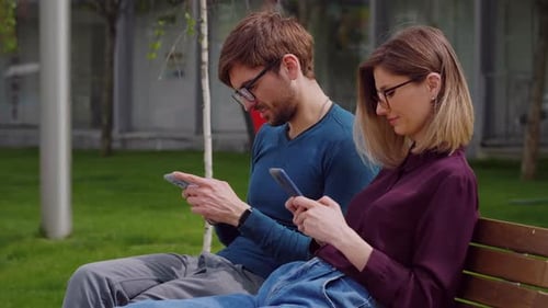 Joven pareja de amigos con teléfonos inteligentes parque al aire libre,