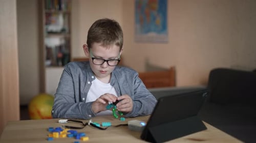Boy Constructing Robot with Tablet in Home
