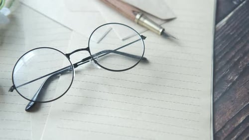 Glasses, Pen, and Paper on Wooden Desk