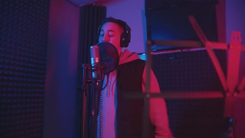 A Man in Headphones Rapping Through the Pop-filter in the Microphone - Recording His Track