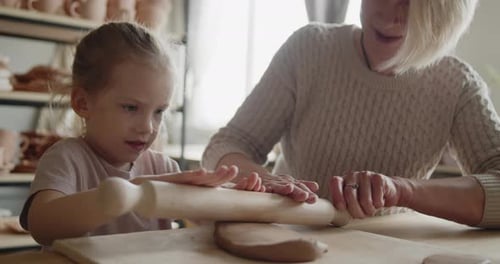 Grandmother Teaches Her Granddaughter to Mold Clay in Pottery Workshop