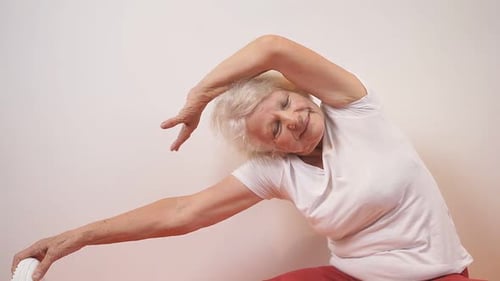 Senior Woman Stretching on Yoga Mat at Home