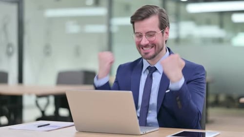 Successful Businessman Working on Laptop Celebrates in Office