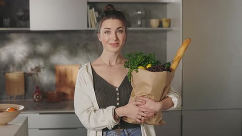 Woman Holding Grocery Bag in Modern Kitchen