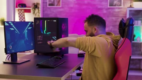 Man Stretches at Computer in Illuminated Room
