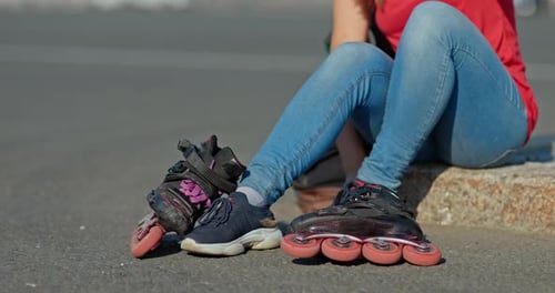 Woman Athlete Puts on Roller Skates on the Street the Beginning of Training
