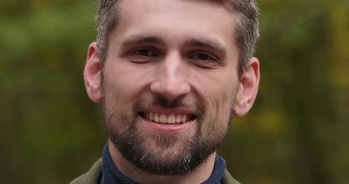 Extreme Close-up of a Smiling Handsome Caucasian Man with Brown Eyes Standing in Forest and Smiling