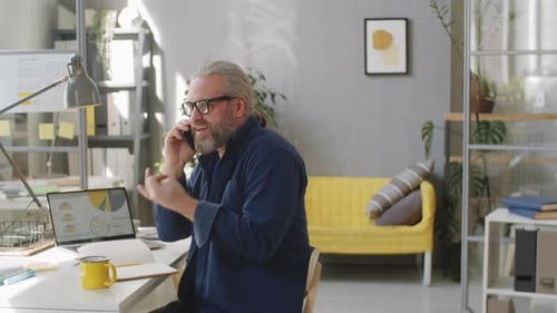 Cheerful Senior Man Talking on Cell Phone in Office
