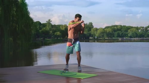 Man Working Out with Resistance Band on Lake Dock
