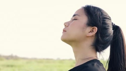 Close-up portrait of young Asian girl relaxed enjoying peaceful sunset.
