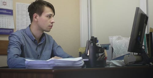 Young Man Working Hard at Computer in Office