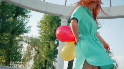 Woman with Balloons Spinning Happily in Gazebo