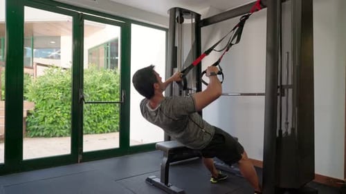Hispanic Sportsman Doing Exercises with Fitness Belts Straps to Strengthen His Abdominal Back
