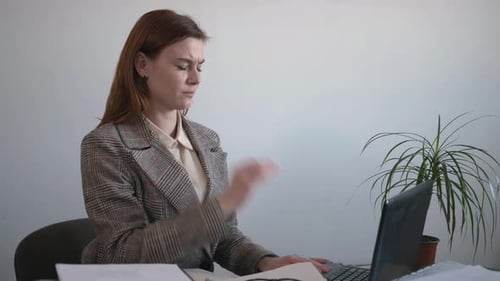 Woman Typing at Desk Stretches Neck at Workplace
