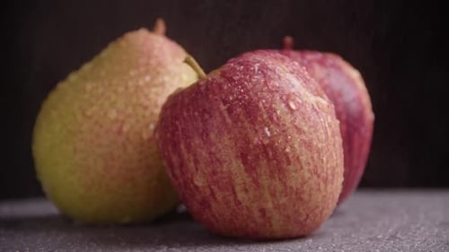 Organic apples and pears slowly rotate on a black background. Harvest of ripe fruits