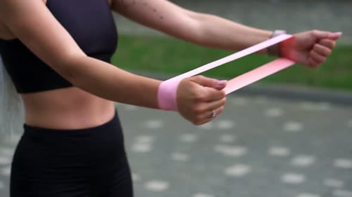 Woman Working Out With Pink Resistance Band Outdoors