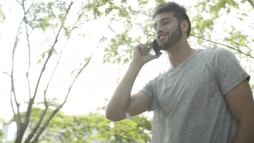 Man Walking in Park Talking on Smartphone