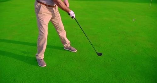 Golfer Swinging Club on Bright Green Golf Course