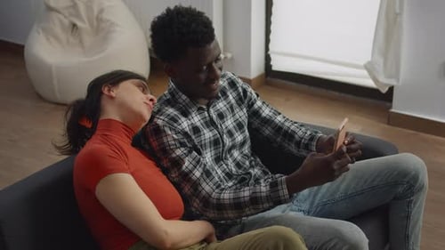 Couple Relaxing Together on Couch Looking at Phone