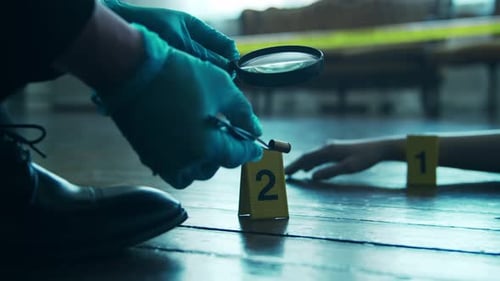 Evidence Examined With Magnifying Glass at Crime Scene