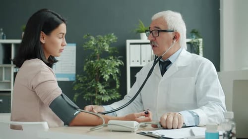 Doctor Checks Young Woman's Blood Pressure in Office