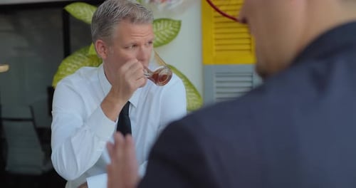 Businessman drinking tea and talking to his colleges during a middle day break.