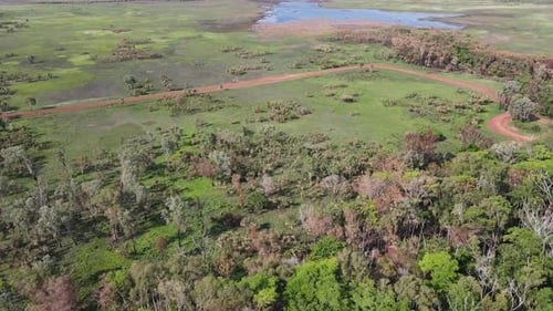 High moving aerial drone shot of Red Road and Green Bushland and Water near Holmes Jungle Nature Par