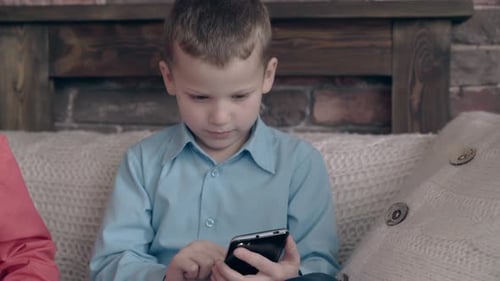 Young Boy Using Smartphone Indoors on Couch