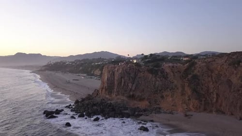 AERIAL: Flight Over Malibu, California View of Beach Shore Line Pacific Ocean at Sunset with