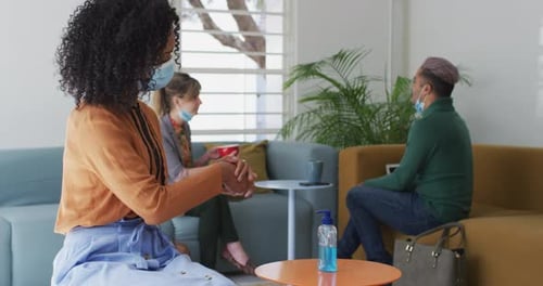 Woman wearing face mask sanitizing her hands at office